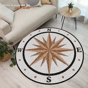 May include: A round rug featuring a compass design. The compass is made of white and brown tiles and has a black border. The rug is on a light wood floor.
