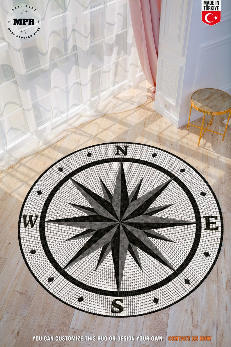 Pode incluir: Um tapete de b&uacute;ssola redondo com um design de mosaico em preto e branco. A b&uacute;ssola aponta para norte, sul, leste e oeste. O tapete &eacute; redondo e tem uma borda preta.