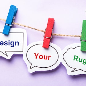 May include: Three white speech bubbles with the words "Design", "Your", and "Rug" written in different colors. The bubbles are hanging on a string with colorful clothespins.