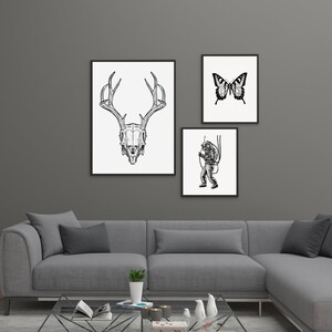 Peut inclure: Trois impressions d'art encadr&eacute;es sur un mur gris. Les impressions pr&eacute;sentent un cr&acirc;ne de cerf en noir et blanc, un papillon et un plongeur. Les impressions sont dans des cadres noirs et sont accroch&eacute;es au-dessus d'un canap&eacute; sectionnel gris.