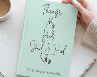 May include: A light mint green hardcover journal with black text that reads Things My Kids Said & Did, featuring a heart icon with two small footprints below the text and the phrase So I'll Always Remember printed at the bottom of the cover.