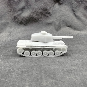 Può includere: Un piccolo modello di carro armato grigio chiaro, con una canna lunga e cingoli dettagliati. Il veicolo militare in miniatura è ambientato su uno sfondo grigio strutturato, che ne evidenzia il design.