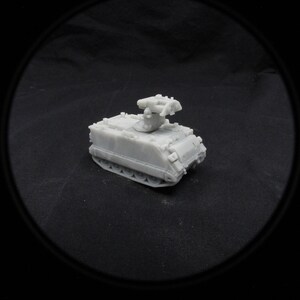 May include: A white plastic model of a military armored personnel carrier with a missile launcher on top.
