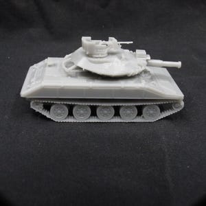 Puede incluir: Un modelo de tanque militar de plástico gris con una torreta giratoria y un cañón. El tanque tiene un sistema de orugas con múltiples ruedas.