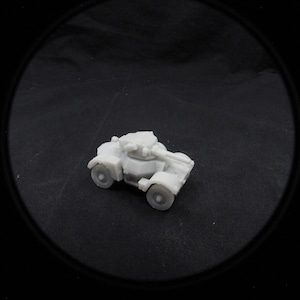 Può includere: Un modello bianco in plastica di un'auto blindata con una torretta e un cannone. Il modello è su una superficie nera.