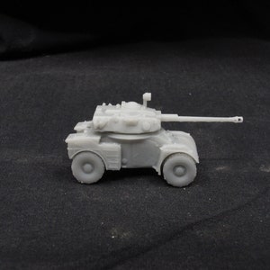 Puede incluir: Un modelo de coche blindado de plástico blanco con una torreta y un cañón. El modelo está en vista lateral y se encuentra sobre una superficie negra.