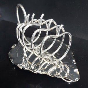 Peut inclure: Porte-serviettes en argent en forme de feuille avec quatre anneaux en forme de pommes.