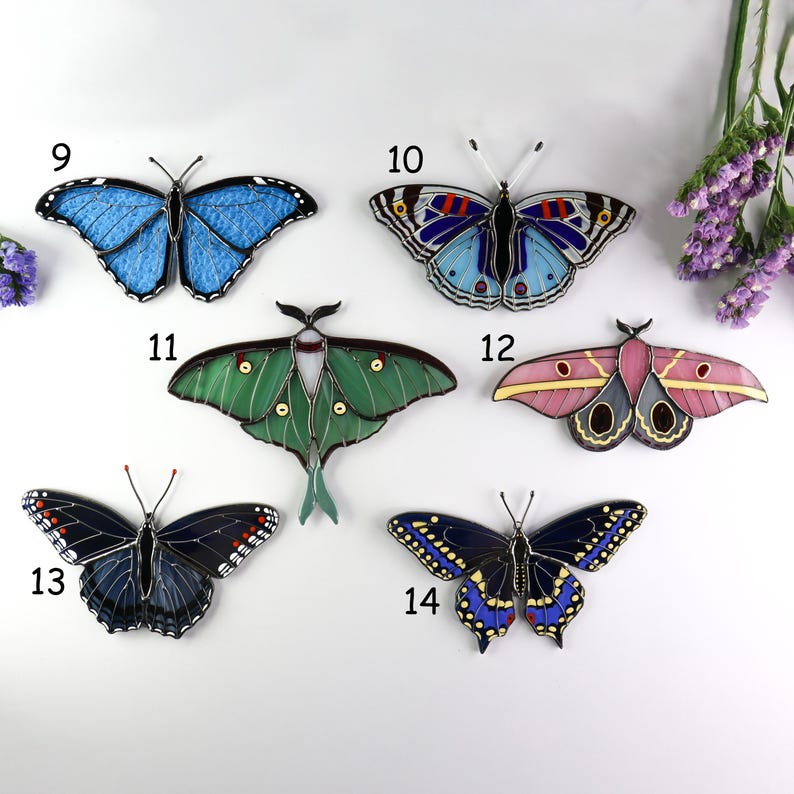 May include: A collection of six colorful butterfly ornaments. The butterflies feature various designs and colors, including blue, green, pink, and black. Each butterfly has a unique pattern and is made of a translucent material.