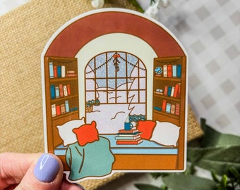 May include: A sticker featuring a cozy window seat with a person reading a book. The window is decorated with a garland and snowflakes, and the scene is set in a snowy winter landscape. The sticker is perfect for adding a touch of whimsy to your home decor.