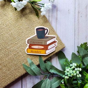 May include: A sticker with a stack of three books, a cup of coffee on top, and the words "Fantasy Reader". The sticker is on a brown burlap background.