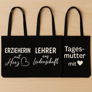Könnte beinhalten: Drei schwarze Tragetaschen mit weißem Text. Die Taschen tragen die Aufschrift "ERZIEHERIN mit Herz", "LEHRER aus Leidenschaft" und "Tagesmutter mit" mit einem Herzsymbol. Jede Tasche hat einen schwarzen Griff.