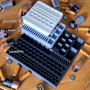 Könnte beinhalten: Drei gestapelte Batterie-Organizer in Weiß, Hellgrau und Dunkelgrau mit Waben- und rechteckigen Fächern. Das weiße Fach misst 117 x 117 mm, das graue Fach 115 x 141 mm und das große dunkle Fach 210 x 220 mm.