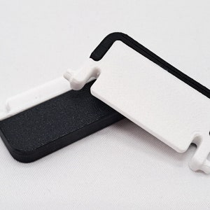 May include: Two white and black rectangular plastic objects. One is white with a black border, and the other is black with a white border. Both have a small, white, protruding tab on one side.