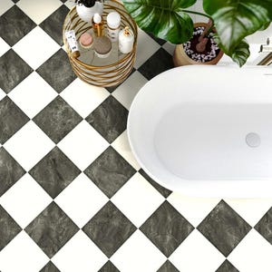 May include: A bathroom floor featuring a diamond-patterned tile design with alternating solid white squares and dark grey marble-textured squares. A white oval bathtub, a gold wire side table with toiletries, and a green potted plant are visible.