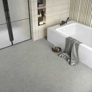 May include: A contemporary bathroom featuring a white bathtub, a grey towel, and a small wooden tray with toiletries. The room has a neutral colour scheme with grey flooring and a light-coloured wall. A glass shower door is visible.
