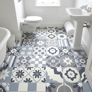 May include: A bathroom floor featuring square tiles with a repeating pattern in shades of blue, gray, and white. The tiles display various geometric, floral, and checkered motifs arranged in a grid, creating a decorative surface throughout the room.