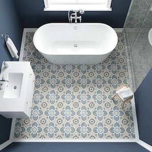 以下が含まれることがあります： 白い楕円形のバスタブ、白い洗面台、模様入りのタイル張りの床があるモダンなバスルームの俯瞰図。床は青、ベージュ、白の花柄です。壁は濃い青色に塗られており、小さな木製のスツールには白いタオルが置かれています。
