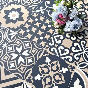 May include: A patterned tile surface with a variety of floral and geometric designs in navy blue, beige, and white. A bouquet of blue, pink, and white flowers rests on the tiles, adding a touch of color and contrast to the overall design.