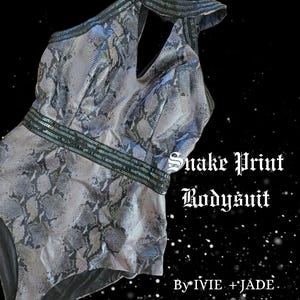 May include: A gray and black snake print bodysuit with a black halter neckline and a black band with silver sequins around the waist. The text "Snake Print Bodysuit" and "By IVIE + JADE" is printed on the image.