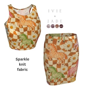 May include: A two-piece outfit featuring a crop top and a mini skirt. The set is made of sparkle knit fabric and has a repeating pattern of zebras, daisies, and a checkered background in shades of orange, white, and green. The text "Sparkle knit fabric" is also visible.