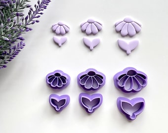 May include: Set of six purple plastic cookie cutters shaped like flowers. The cutters are arranged in three rows of two, with the top row showing the full flower, the middle row showing the flower without the center, and the bottom row showing the center of the flower.