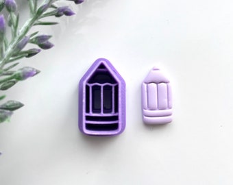 May include: Two purple pencil shaped polymer clay charms. One charm is a mold and the other is a solid charm.