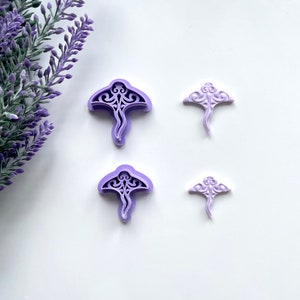 May include: Two sets of purple plastic cookie cutters shaped like stingrays. The larger cutters have intricate designs and the smaller cutters are simpler.