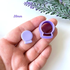May include: Purple plastic cookie cutters in the shape of a snow globe. The cutters are 20mm in size.