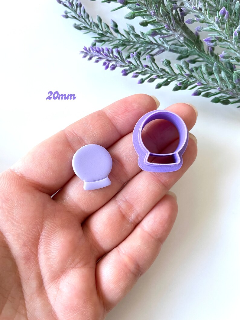 May include: Purple plastic cookie cutters in the shape of a snow globe. The cutters are 20mm in size.