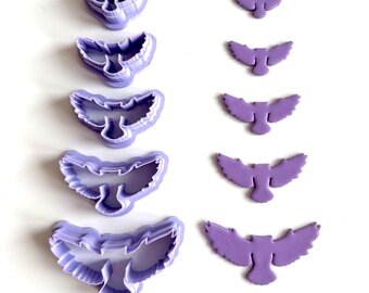 May include: A collection of purple owl-shaped cookie cutters and fondant cutouts. The cutters are in various sizes, with detailed wing and body shapes. The cutouts are solid purple, also in different sizes, perfect for baking and crafting.