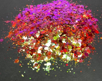 May include: A pile of iridescent glitter in shades of purple, orange, and gold. The glitter is scattered on a black surface.