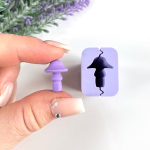 May include: A purple silicone mold for making mushroom-shaped resin crafts. The mold is open and shows the shape of the mushroom. A small purple mushroom made with resin is shown next to the mold.