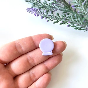 May include: A small, lavender-colored, ceramic,  decorative,  globe-shaped ornament.