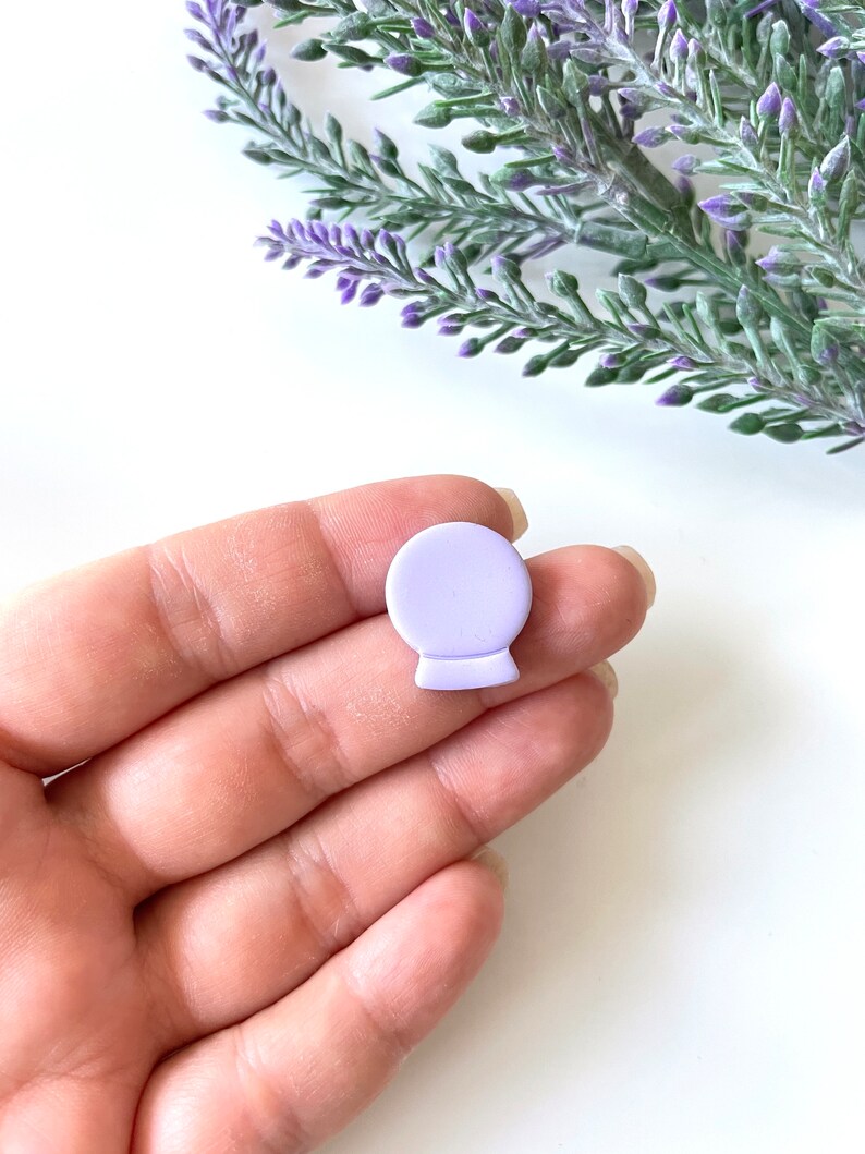 May include: A small, lavender-colored, ceramic,  decorative,  globe-shaped ornament.
