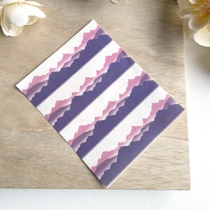 May include: A sheet of decorative paper with a repeating pattern of purple and pink mountain ranges on a white background.