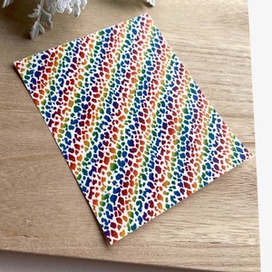 May include: A sheet of rainbow leopard print patterned paper. The pattern is a white background with a rainbow coloured leopard print.