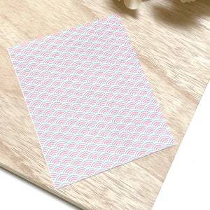 May include: A sheet of white paper with a repeating pattern of pink and blue overlapping semi-circles.