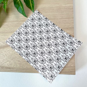 May include: A white sheet of paper with a black and white damask pattern featuring skulls. The pattern is repeated throughout the sheet.