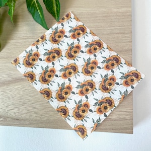May include: White background with a repeating pattern of yellow sunflowers with brown centers and green leaves.