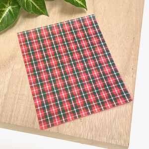 Peut inclure: Feuille de vinyle à motif écossais rouge et vert. Le vinyle est sur une surface en bois brun clair.