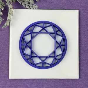 May include: A blue plastic geometric design in the shape of a diamond. The design is on a white background.