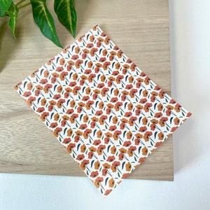 May include: A white card with a repeating pattern of orange and brown flowers on a white background.