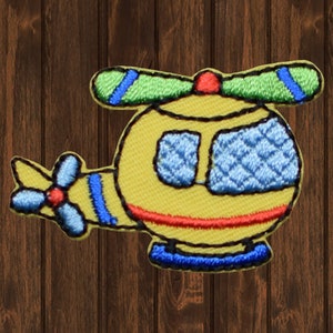 May include: A yellow helicopter applique with blue and green details. The helicopter has a red propeller and blue windows.