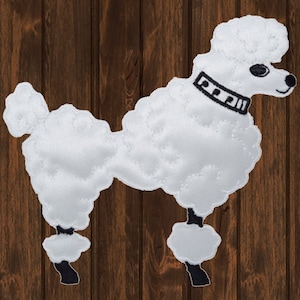 May include: White felt poodle applique with black stitching and a black collar. The poodle is standing on a brown wooden background.