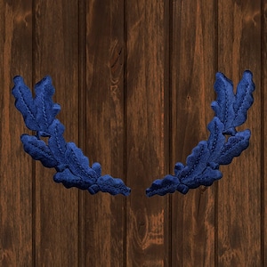 Peut inclure: Deux couronnes de feuilles de chêne en tissu bleu sur un fond en bois brun.