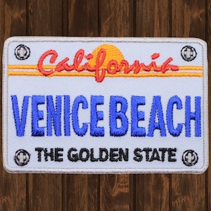 以下が含まれることがあります： 「カリフォルニア」の文字と黄色の太陽、「ベニスビーチ」、「ゴールデンステート」の文字が刺繍された白と青のワッペン。