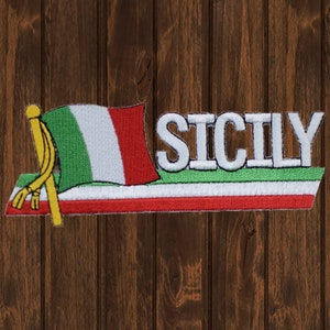 May include: A white embroidered patch with the word "SICILY" in white letters on a green background. A small Italian flag with a yellow pole is attached to the left side of the patch.