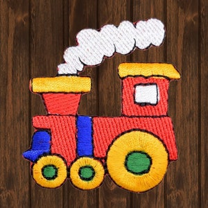 May include: A red, yellow, and blue embroidered train with a white smoke plume. The train has three wheels and a large yellow wheel in the back.