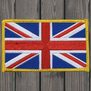 Pode incluir: Um pequeno remendo bordado com o design da bandeira Union Jack. A bandeira é vermelha, branca e azul com uma borda amarela.