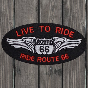 Puede incluir: Parche ovalado negro con alas blancas y un letrero blanco de la Ruta 66 con texto rojo. El texto en el parche dice "Live to Ride" y "Ride Route 66".